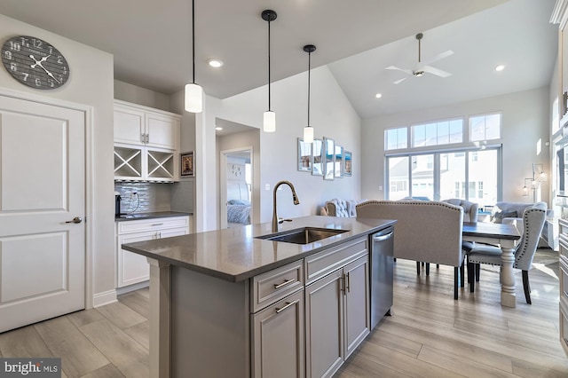 kitchen featuring a center island with sink, light wood-type flooring, pendant lighting, sink, and white cabinets