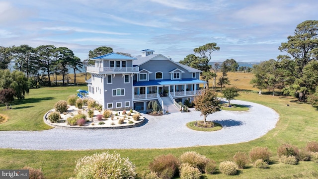 rear view of property with a lawn, a balcony, and covered porch