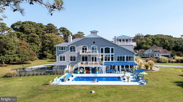 back of property with a patio area, a balcony, a fenced in pool, and a yard