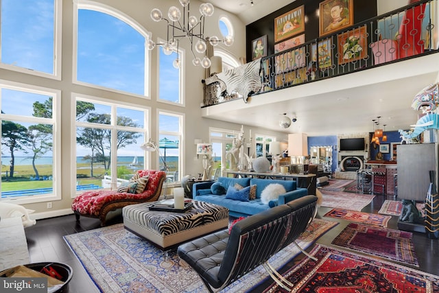 living room featuring plenty of natural light, hardwood / wood-style floors, a high ceiling, and a notable chandelier