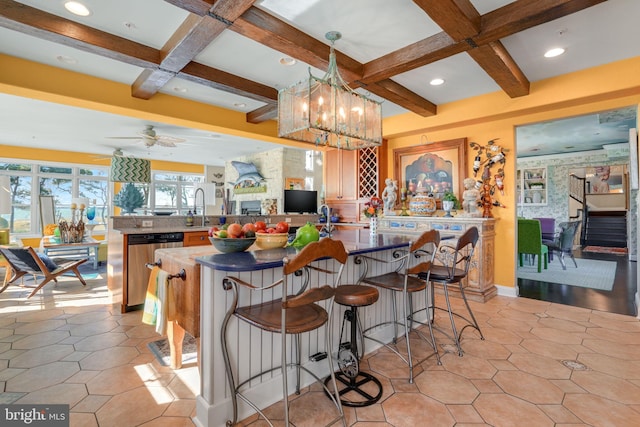 kitchen with kitchen peninsula, a kitchen breakfast bar, ceiling fan with notable chandelier, beam ceiling, and hanging light fixtures