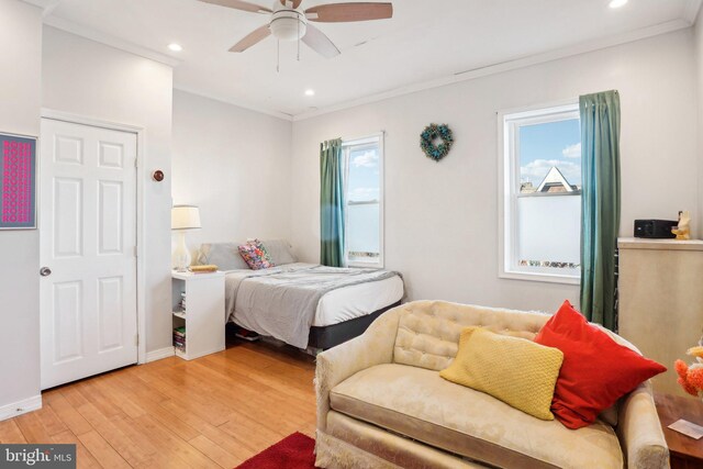 bedroom with multiple windows, ceiling fan, crown molding, and wood-type flooring