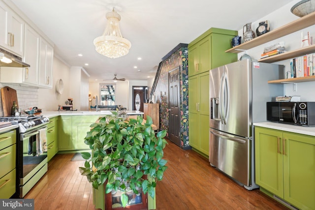 kitchen featuring dark hardwood / wood-style flooring, backsplash, ceiling fan with notable chandelier, stainless steel appliances, and green cabinetry