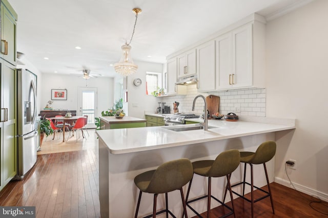 kitchen featuring white cabinets, a breakfast bar area, dark hardwood / wood-style flooring, kitchen peninsula, and stainless steel appliances