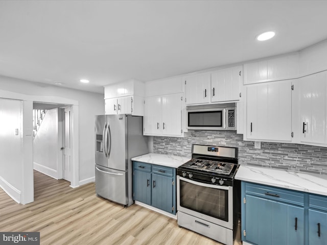 kitchen featuring stainless steel appliances, light hardwood / wood-style floors, white cabinetry, light stone counters, and blue cabinets