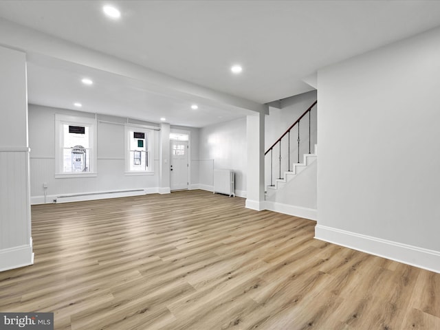 unfurnished living room with a baseboard heating unit, light hardwood / wood-style floors, and radiator heating unit