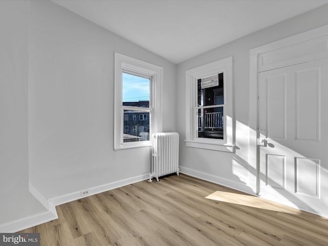 spare room featuring radiator, vaulted ceiling, and light hardwood / wood-style flooring