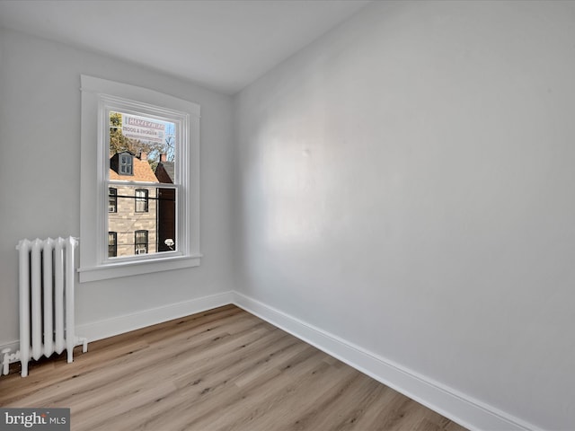 empty room with light hardwood / wood-style floors and radiator heating unit