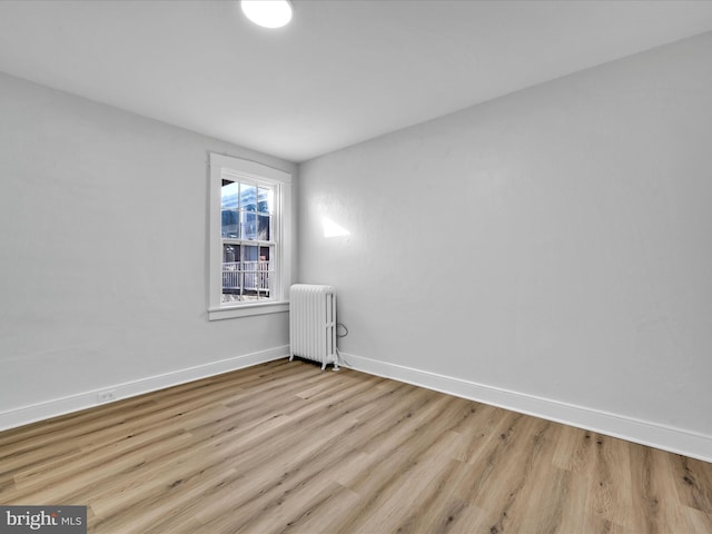 unfurnished room featuring radiator heating unit and light hardwood / wood-style flooring