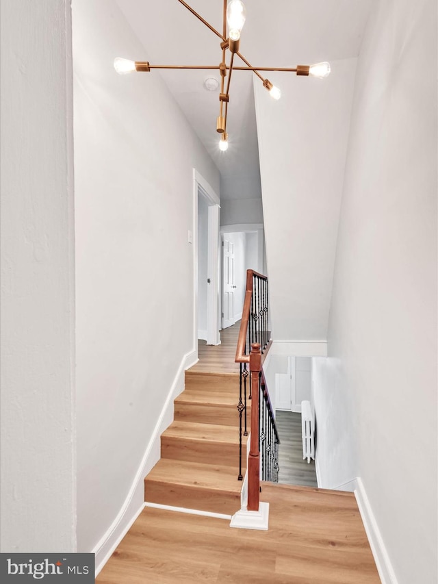 stairs featuring hardwood / wood-style flooring and a chandelier