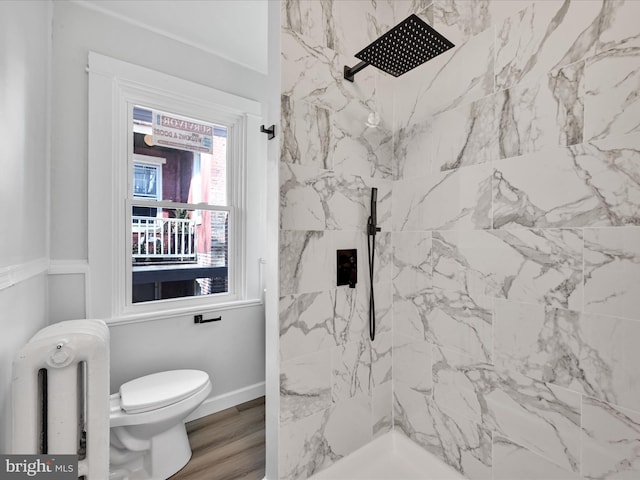 bathroom with toilet, radiator, hardwood / wood-style floors, and a tile shower