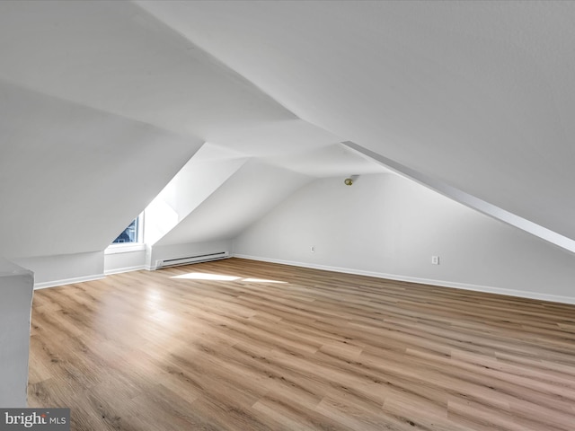 bonus room featuring vaulted ceiling with skylight, baseboard heating, and light hardwood / wood-style flooring