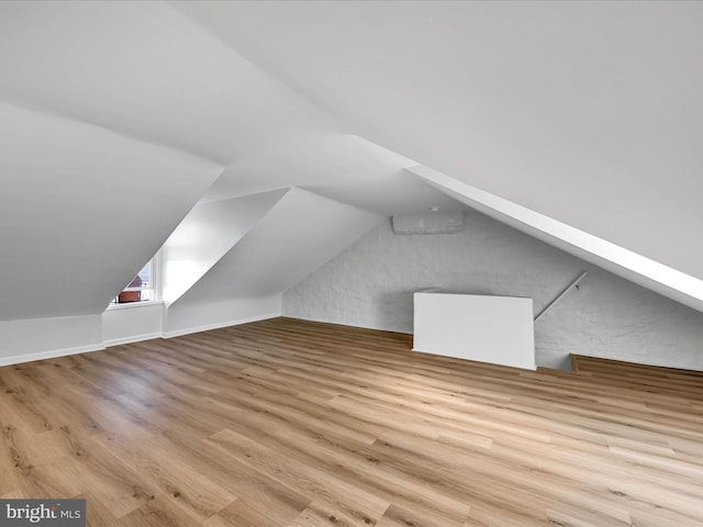 additional living space with light hardwood / wood-style flooring and lofted ceiling with skylight