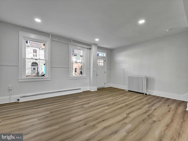 spare room featuring radiator, baseboard heating, and light wood-type flooring