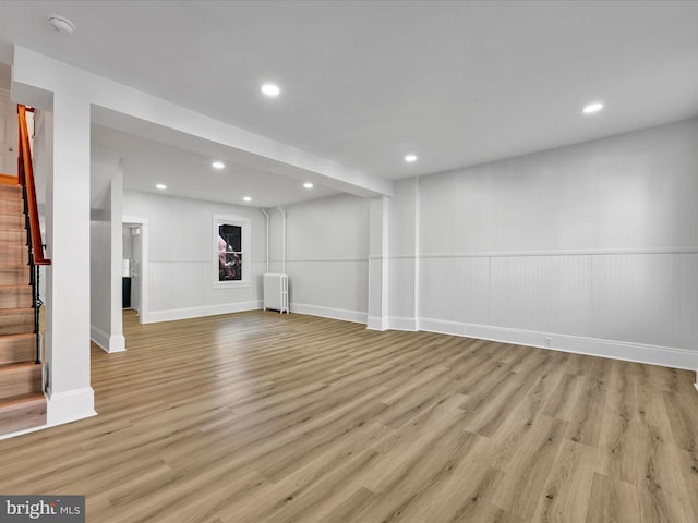 basement with light hardwood / wood-style floors and radiator heating unit