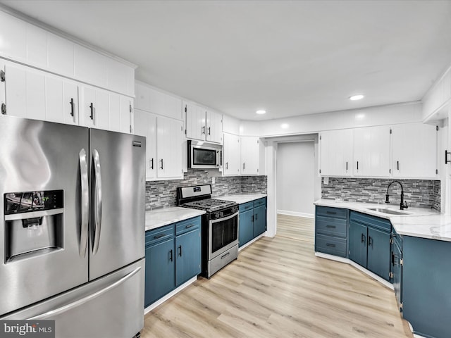 kitchen featuring stainless steel appliances, light hardwood / wood-style floors, blue cabinets, sink, and white cabinetry