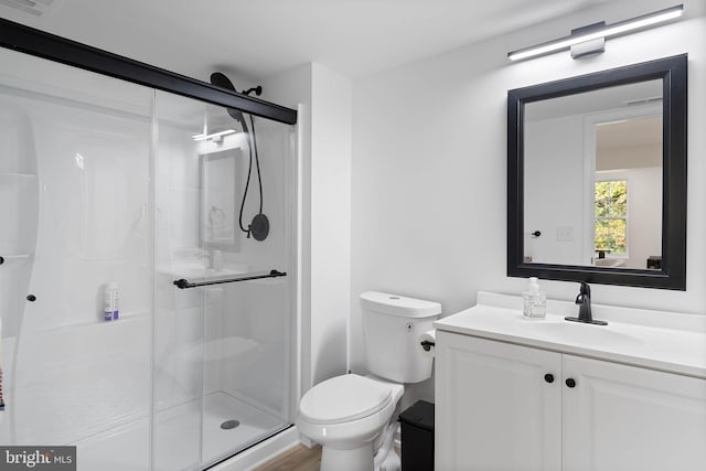 bathroom featuring vanity, toilet, and a shower with door