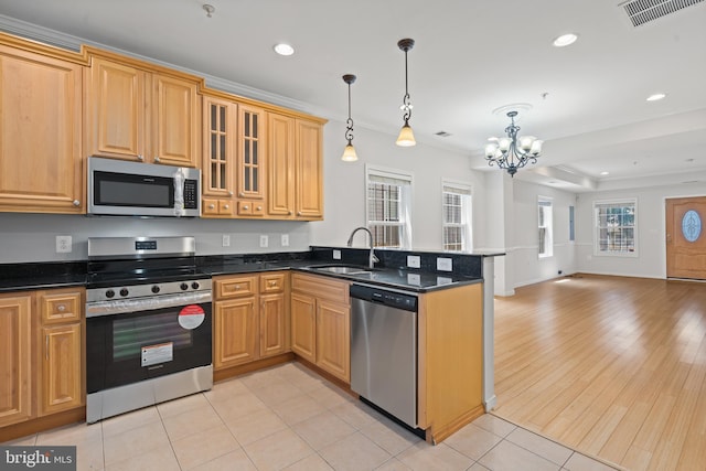 kitchen featuring appliances with stainless steel finishes, sink, light wood-type flooring, hanging light fixtures, and a chandelier