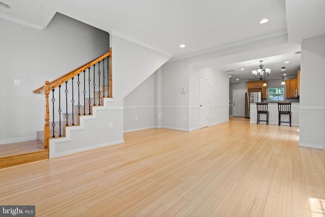 unfurnished living room with light hardwood / wood-style floors, a notable chandelier, and ornamental molding