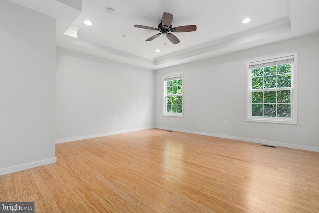 unfurnished room featuring light hardwood / wood-style floors, a raised ceiling, ornamental molding, and ceiling fan