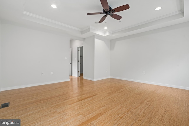 spare room featuring crown molding, a tray ceiling, and light hardwood / wood-style floors