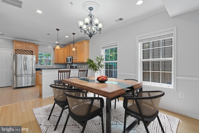 dining space with a healthy amount of sunlight, crown molding, a notable chandelier, and light hardwood / wood-style floors