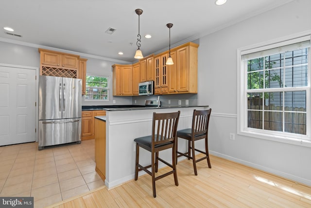 kitchen featuring appliances with stainless steel finishes, kitchen peninsula, and a healthy amount of sunlight