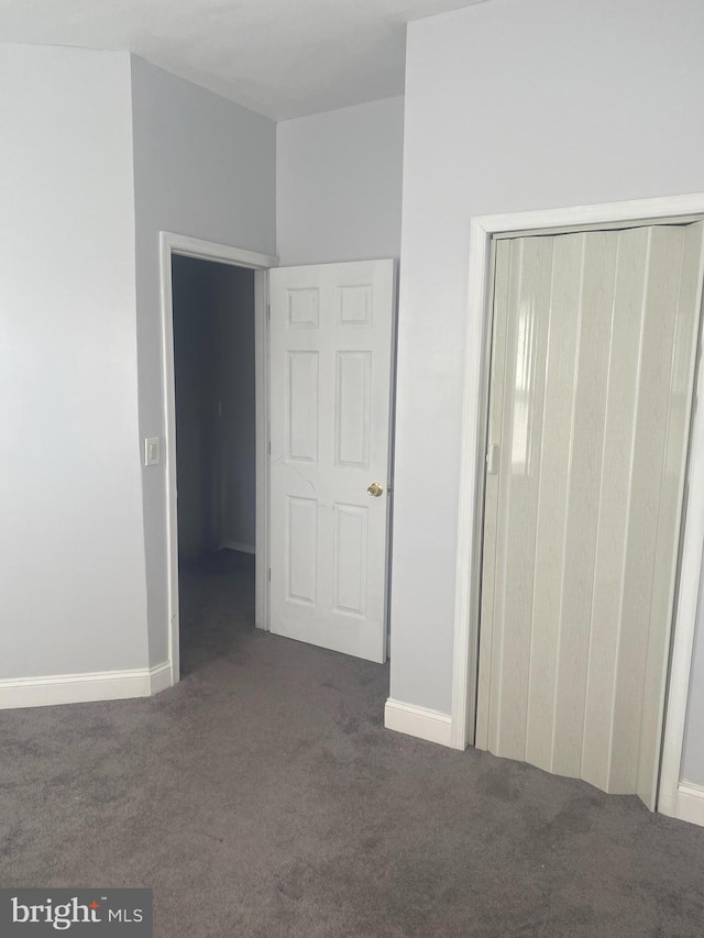 unfurnished bedroom featuring dark colored carpet and a closet