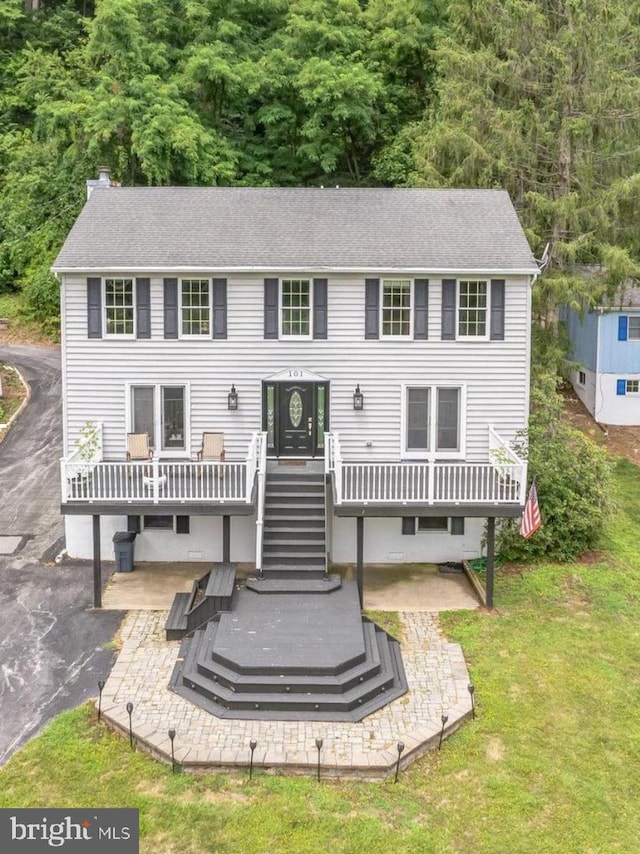 rear view of house with a wooden deck, a lawn, and a patio area