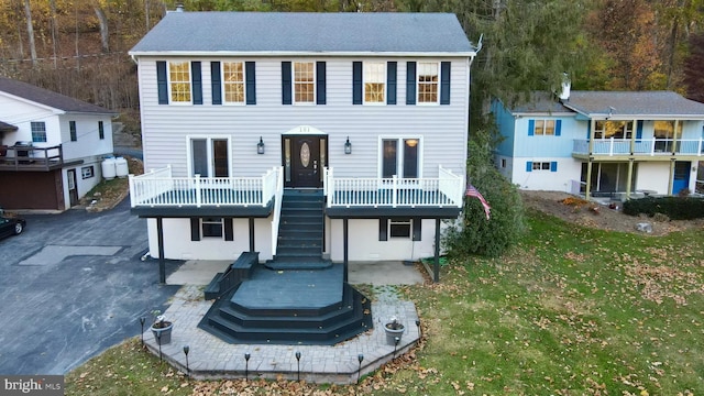 view of front of house with a front yard, a balcony, and a patio area