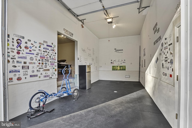 garage with a garage door opener and stainless steel fridge