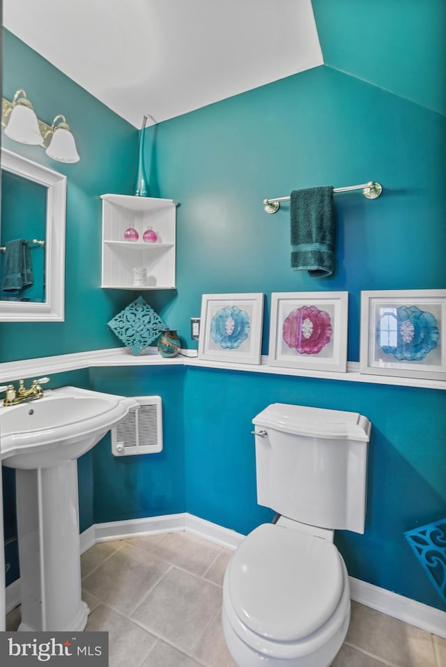 bathroom with heating unit, sink, tile patterned flooring, toilet, and lofted ceiling