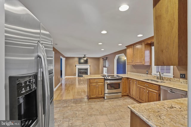 kitchen with kitchen peninsula, sink, light stone counters, and stainless steel appliances