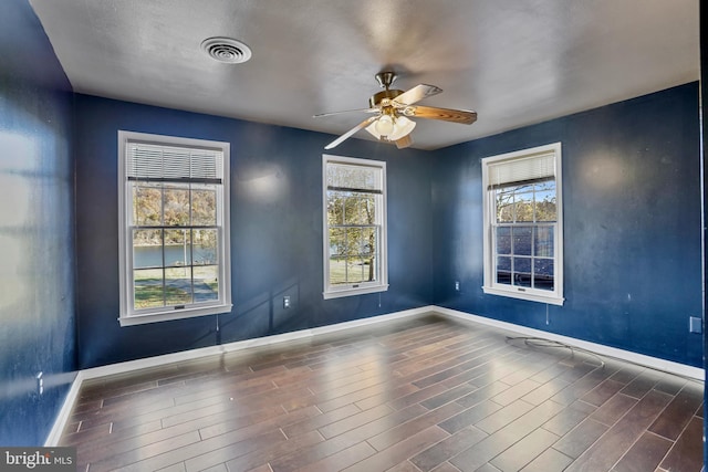 empty room with dark hardwood / wood-style flooring and ceiling fan