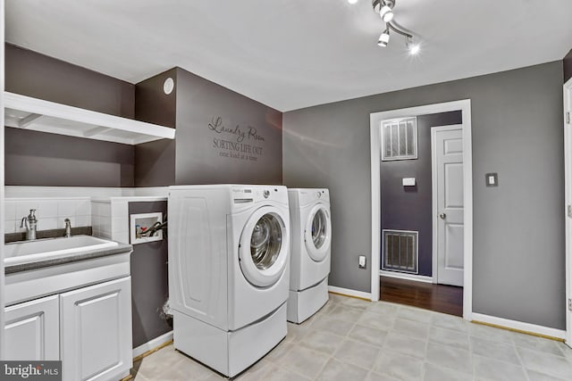 clothes washing area featuring sink, cabinets, and independent washer and dryer