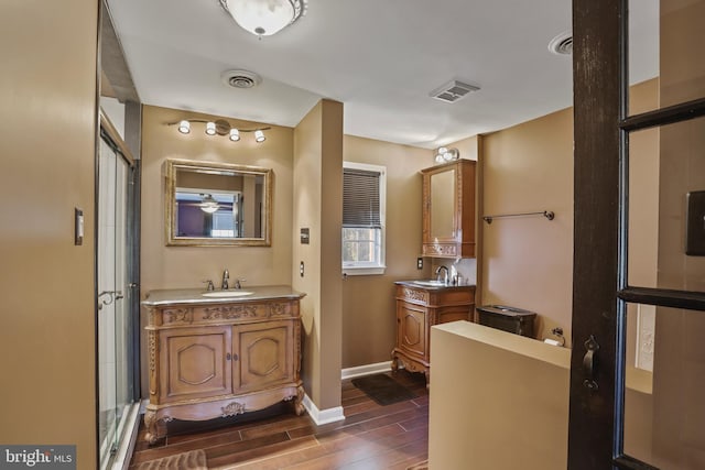 bathroom with wood-type flooring, vanity, and a shower with door