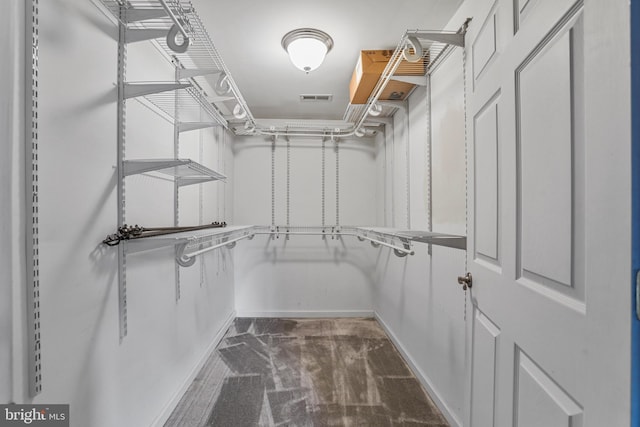 spacious closet with dark colored carpet