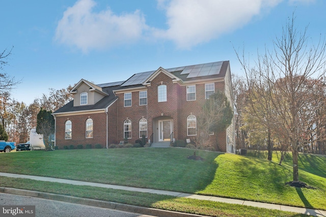 view of front of home with a front yard and solar panels