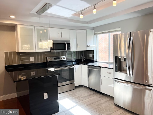 kitchen with white cabinetry, stainless steel appliances, sink, and backsplash