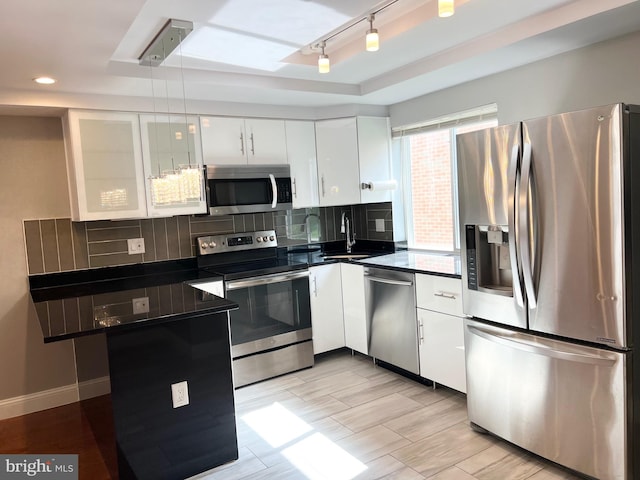 kitchen featuring appliances with stainless steel finishes, white cabinetry, sink, and backsplash