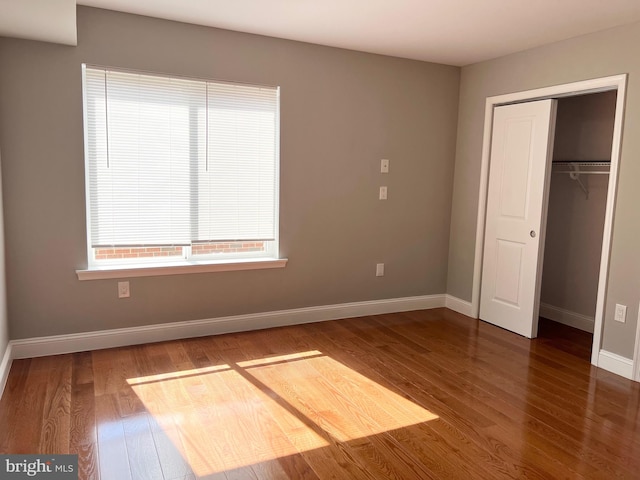 unfurnished bedroom with dark wood-type flooring and a closet