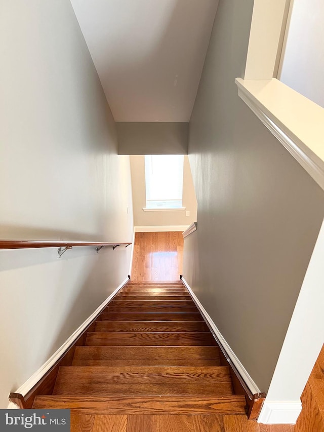 staircase with wood-type flooring and lofted ceiling