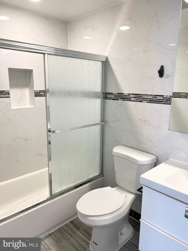 full bathroom with vanity, enclosed tub / shower combo, tile walls, and toilet