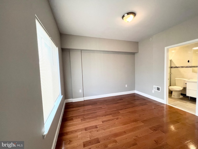 unfurnished bedroom featuring connected bathroom and hardwood / wood-style floors