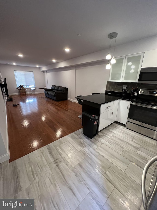 kitchen featuring light hardwood / wood-style flooring, hanging light fixtures, stainless steel appliances, kitchen peninsula, and white cabinets