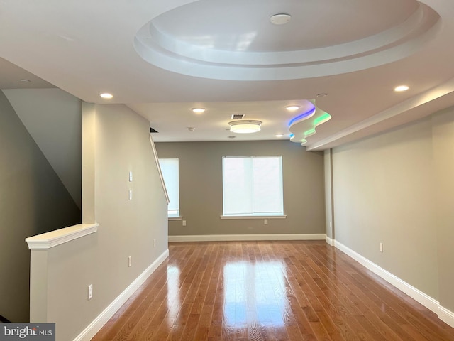 empty room with hardwood / wood-style flooring and a tray ceiling