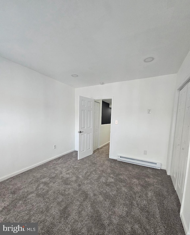 carpeted spare room with a baseboard heating unit