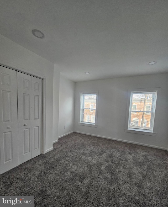 unfurnished bedroom with a closet and dark colored carpet