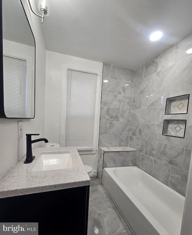 bathroom with a bathtub, vanity, and toilet