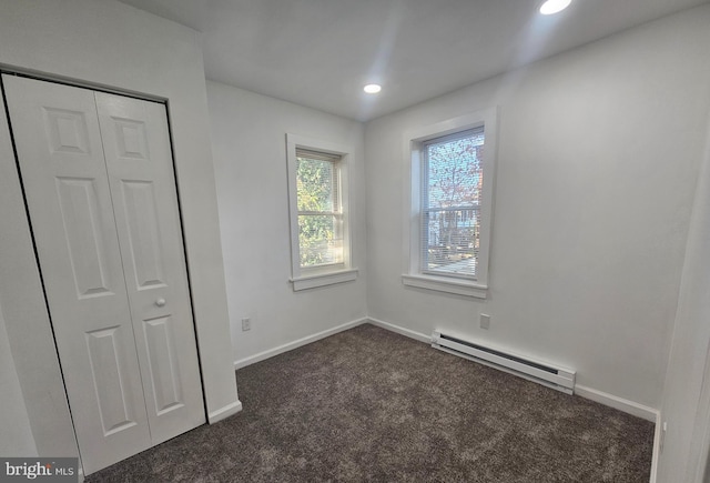 unfurnished bedroom with a baseboard radiator, a closet, and dark carpet